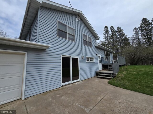439 270th Ave, Cumberland, WI 54829 - back of property featuring a lawn, a wooden deck, a patio area, and a garage