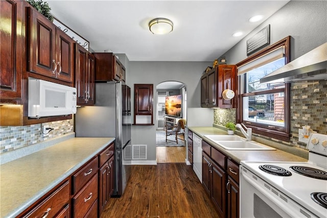 kitchen with a sink, white appliances, arched walkways, visible vents, and dark wood-style floors