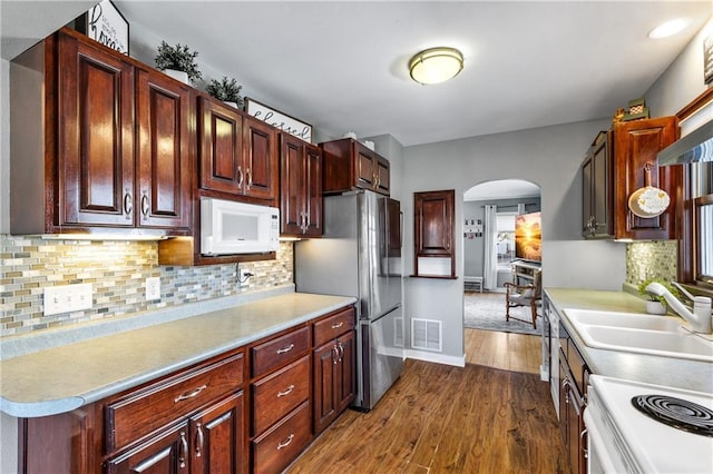 kitchen with visible vents, arched walkways, appliances with stainless steel finishes, dark wood finished floors, and light countertops