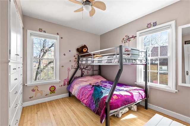 bedroom featuring baseboards, multiple windows, and light wood-type flooring