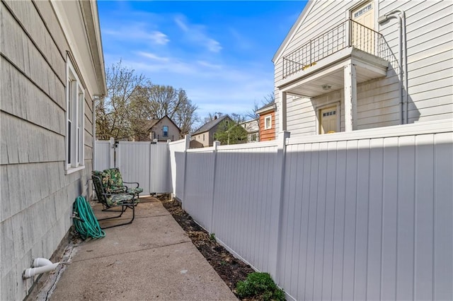 view of side of home with a balcony and a fenced backyard