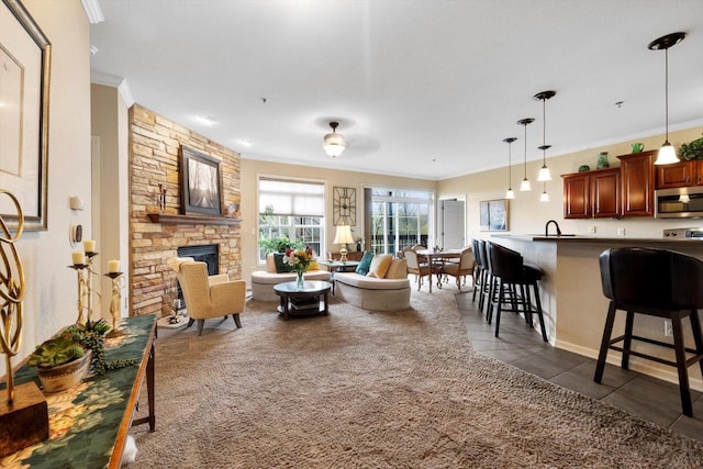 living room with dark tile patterned flooring, ornamental molding, and a fireplace