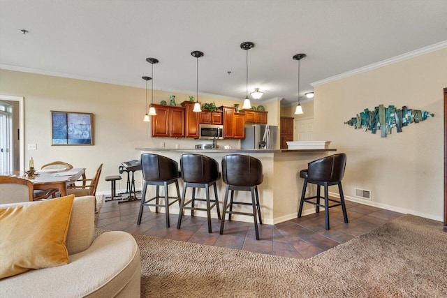 kitchen with crown molding, appliances with stainless steel finishes, a breakfast bar, a peninsula, and visible vents
