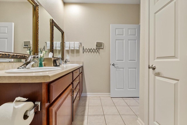 full bathroom with double vanity, baseboards, a sink, and tile patterned flooring