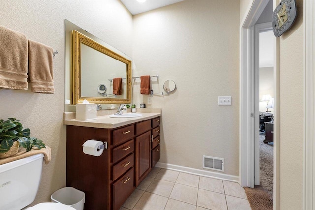 bathroom featuring visible vents, vanity, toilet, baseboards, and tile patterned floors