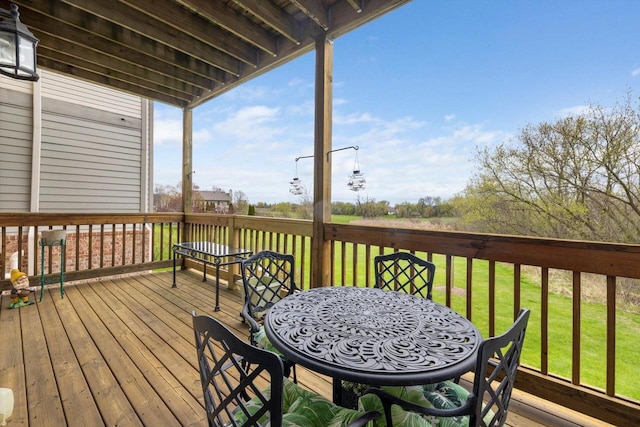 wooden deck featuring a lawn and outdoor dining area