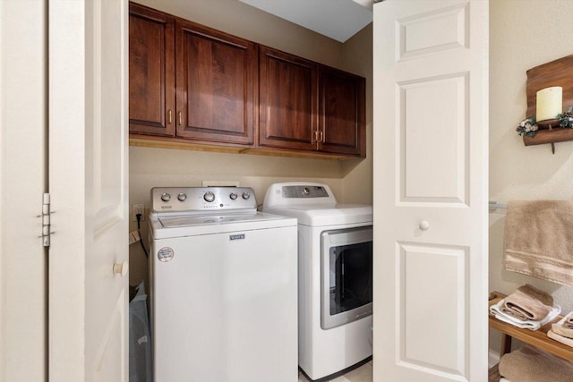 clothes washing area featuring cabinet space and washer and clothes dryer