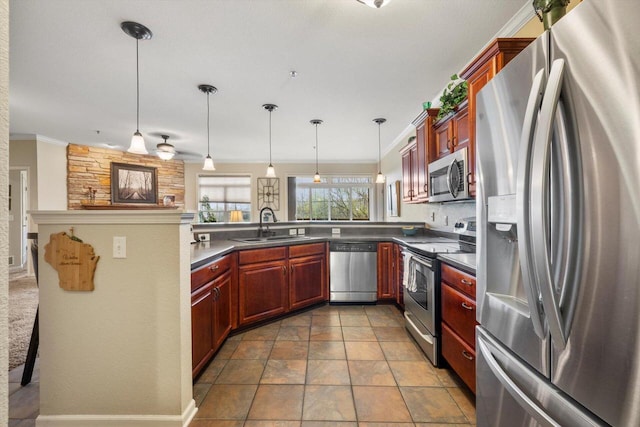 kitchen with ornamental molding, a peninsula, dark countertops, a sink, and stainless steel appliances