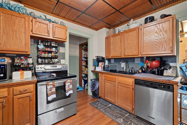 2311 20th St, Racine, WI 53403 - kitchen with decorative backsplash, light wood-style floors, tile counters, a sink, and appliances with stainless steel finishes