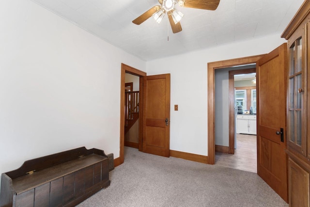 carpeted spare room featuring baseboards and a ceiling fan
