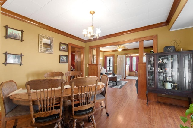 dining room with crown molding, wood finished floors, and ceiling fan with notable chandelier