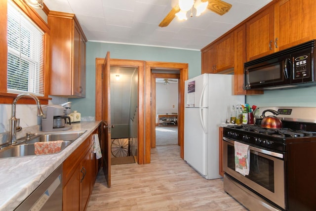 kitchen with ceiling fan, brown cabinets, a sink, light wood-style floors, and stainless steel appliances