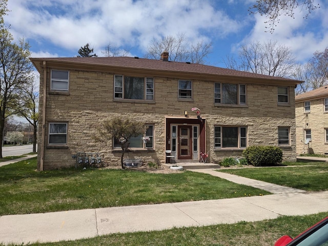 view of front of house featuring a chimney, stone siding, and a front lawn