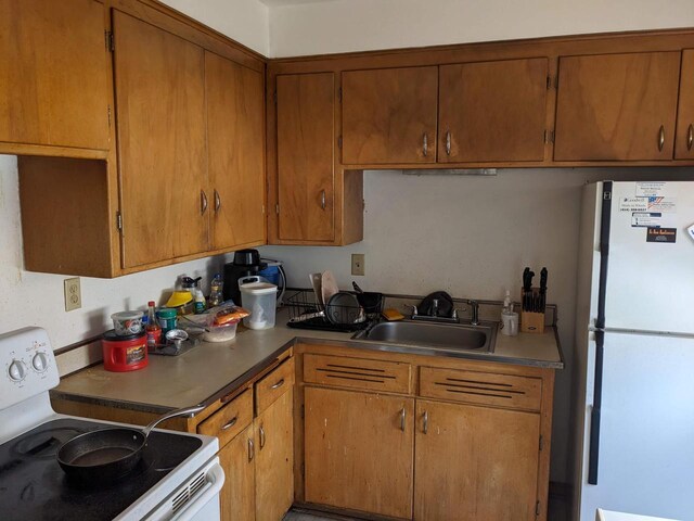 kitchen featuring white appliances, brown cabinets, and a sink