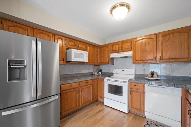 kitchen featuring brown cabinetry, white appliances, light wood-style floors, tile countertops, and under cabinet range hood