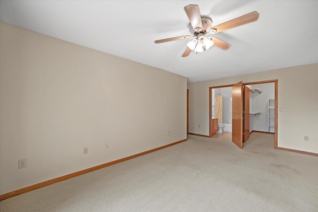 spare room featuring light colored carpet, a ceiling fan, and baseboards