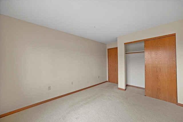 unfurnished bedroom featuring baseboards, light colored carpet, and a closet