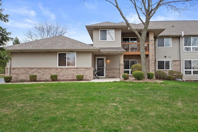 view of front of house with a balcony, a front yard, and brick siding