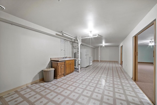 finished below grade area featuring freestanding refrigerator, baseboards, and light floors
