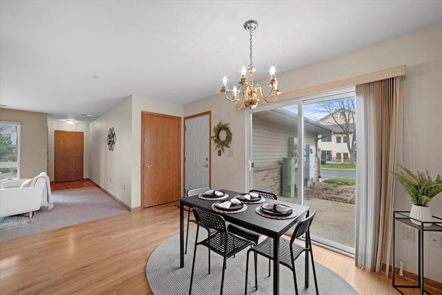 dining room featuring baseboards, light wood-style flooring, and a notable chandelier