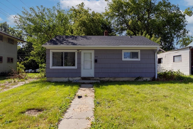 bungalow featuring a chimney, roof with shingles, and a front lawn
