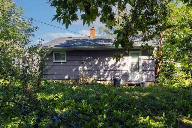 view of home's exterior with roof with shingles and a chimney