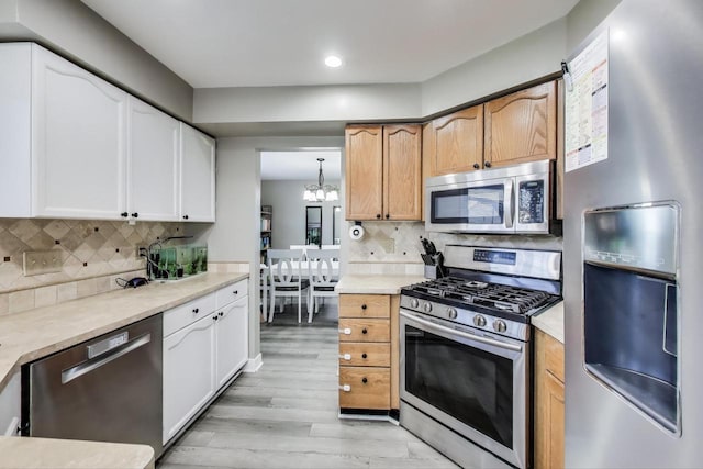 kitchen with recessed lighting, light wood finished floors, backsplash, a notable chandelier, and stainless steel appliances