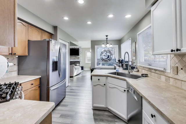 kitchen with appliances with stainless steel finishes, a sink, a chandelier, light wood-style floors, and recessed lighting