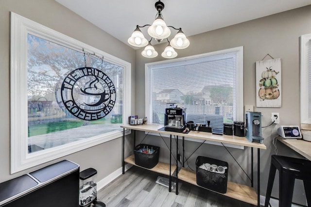 office space with light wood-style floors, baseboards, and a notable chandelier