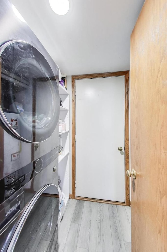 laundry area featuring laundry area, stacked washer and clothes dryer, and wood finished floors