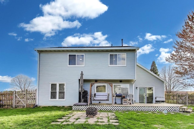 rear view of property featuring a fenced backyard, a fire pit, a wooden deck, and a yard