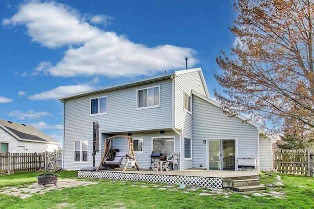 rear view of property featuring a yard, a deck, a fire pit, and a fenced backyard