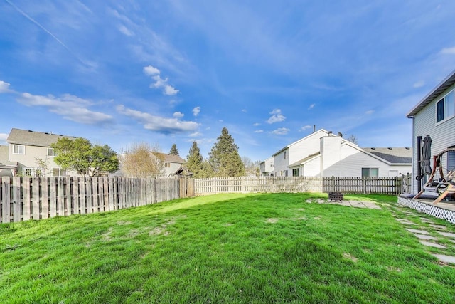 view of yard featuring a residential view, a fenced backyard, and an outdoor fire pit