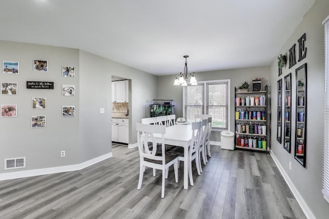 dining space featuring visible vents, light wood-style flooring, baseboards, and a chandelier