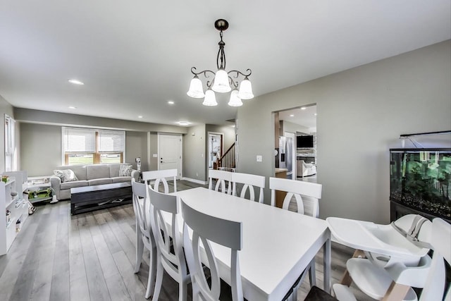 dining area featuring recessed lighting, an inviting chandelier, wood finished floors, and stairway