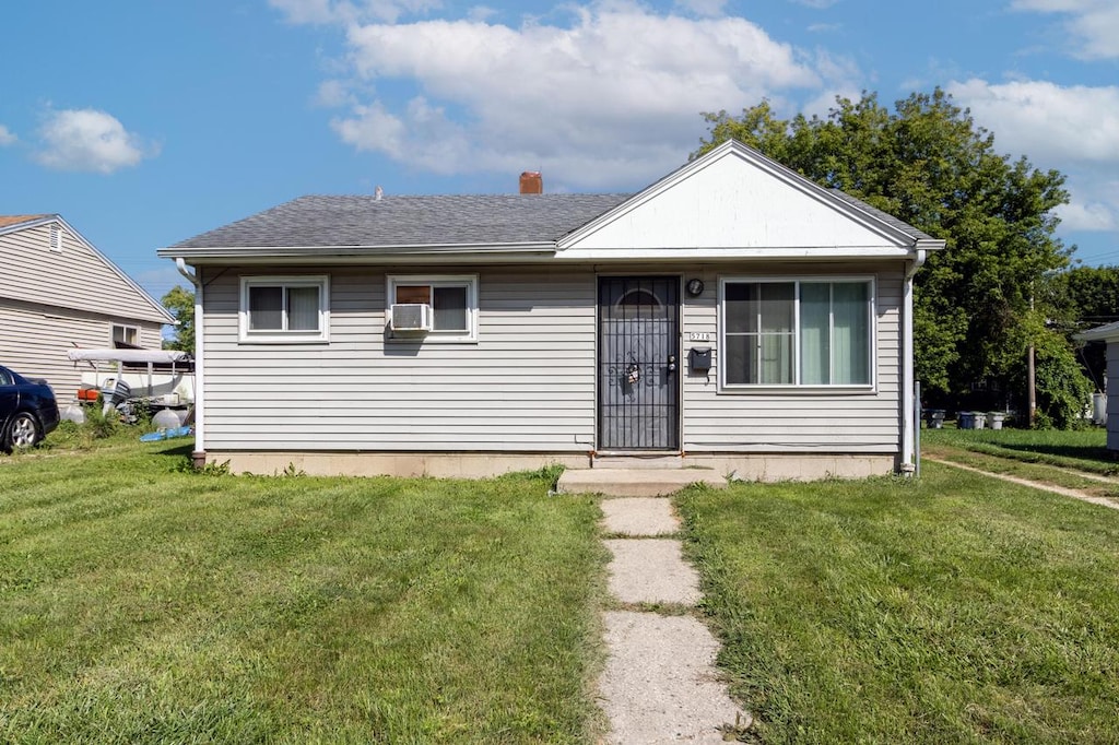 bungalow-style home with a shingled roof, a front lawn, and a chimney