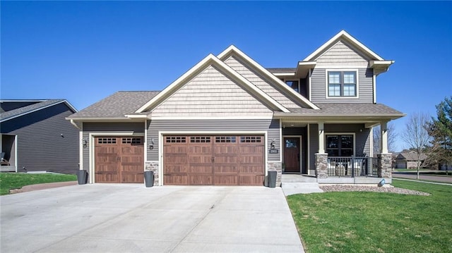 2931 Drier Rd, Eau Claire, WI 54701 - craftsman house featuring covered porch, a front lawn, concrete driveway, an attached garage, and stone siding