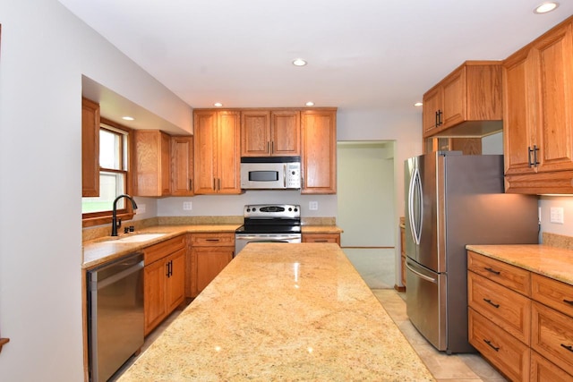 kitchen with stainless steel appliances, a sink, recessed lighting, light stone countertops, and brown cabinets