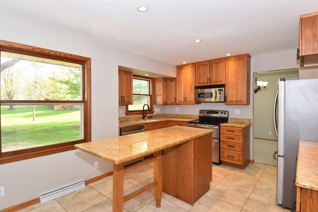 kitchen featuring stainless steel appliances, a sink, light stone counters, recessed lighting, and brown cabinetry
