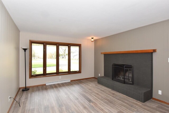 unfurnished living room featuring a baseboard heating unit, light wood-type flooring, a brick fireplace, and baseboards