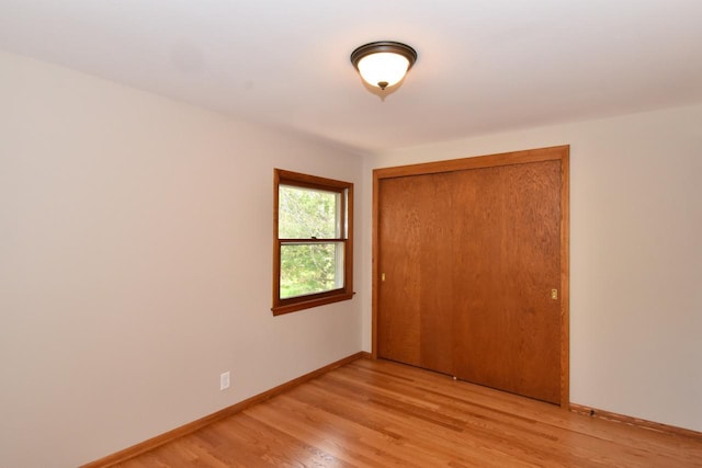 unfurnished bedroom featuring light wood finished floors, a closet, and baseboards