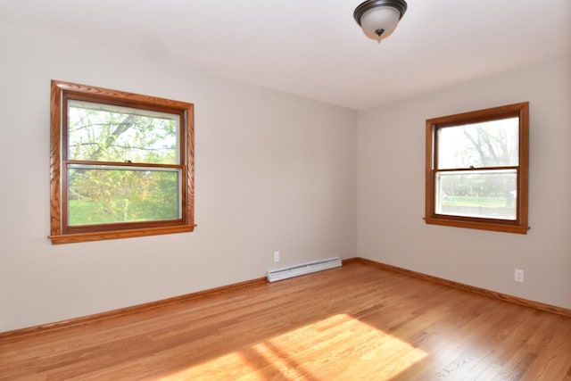 empty room featuring baseboard heating, light wood-style floors, and baseboards