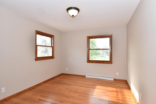 empty room with baseboard heating, healthy amount of natural light, light wood-style flooring, and baseboards
