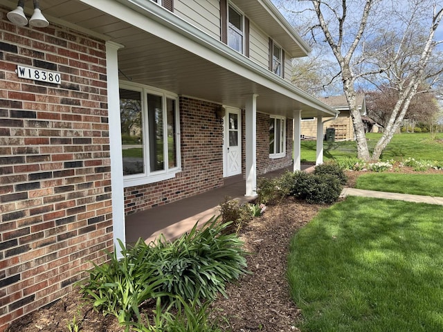 view of home's exterior with a porch, brick siding, and a lawn