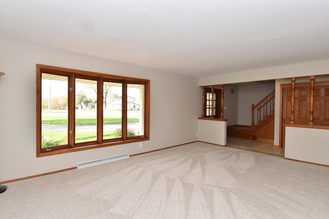 unfurnished living room with light carpet, baseboard heating, stairway, and baseboards