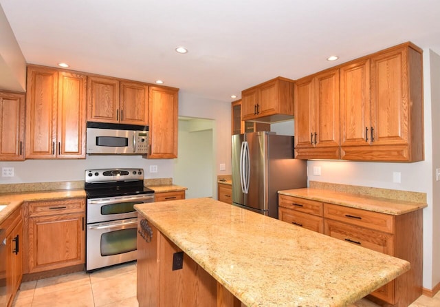 kitchen with stainless steel appliances, recessed lighting, light stone countertops, light tile patterned flooring, and brown cabinetry