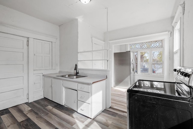 kitchen with dark wood-style flooring, a sink, light countertops, white cabinetry, and stainless steel electric stove