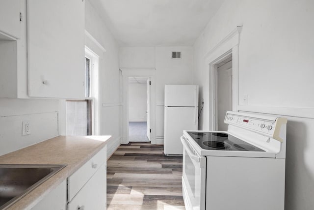 kitchen featuring visible vents, white cabinets, and white appliances