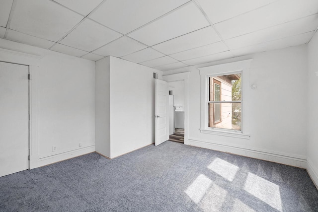 carpeted empty room with visible vents, a paneled ceiling, and baseboards