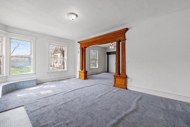 empty room with crown molding, baseboards, carpet flooring, and ornate columns
